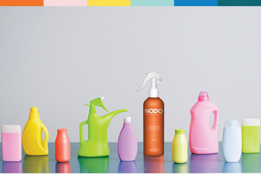 Toutes sortes de bouteille colorées dont une bouteille de neutralisant d'odeurs NODO à l'arôme d'abricot avec la barre horizontale signature de NODO