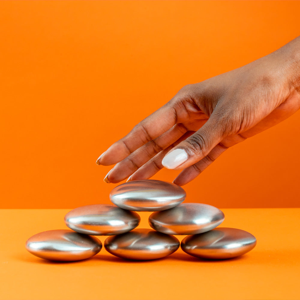 mains qui prend un savon qui enleve les odeurs en inox sur fond orange