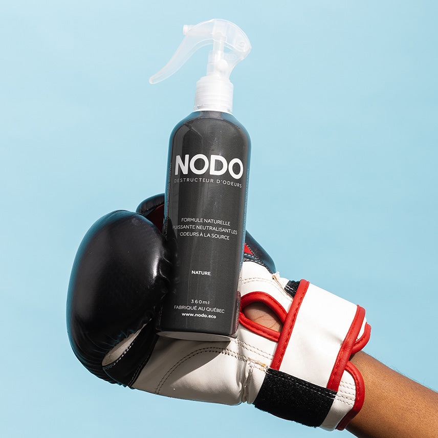 Bouteille de NODO sans arôme ajouté tenu dans une main portant un gant de boxe.
